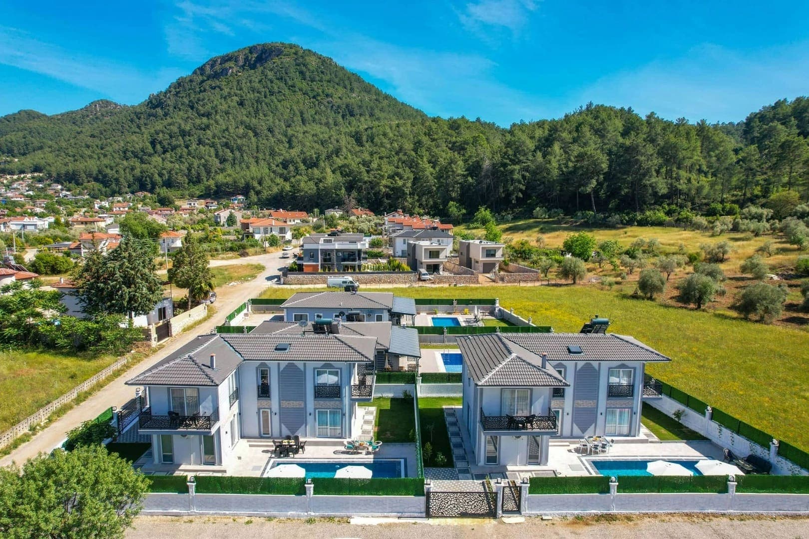 Dağ yamacındaki villaların havuzlu avlularının havadan görünümü