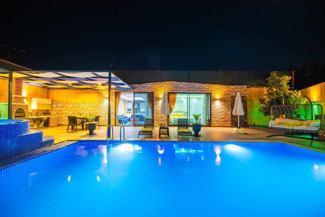 Gece aydınlatmalı havuz ve havuz başı oturma alanı
