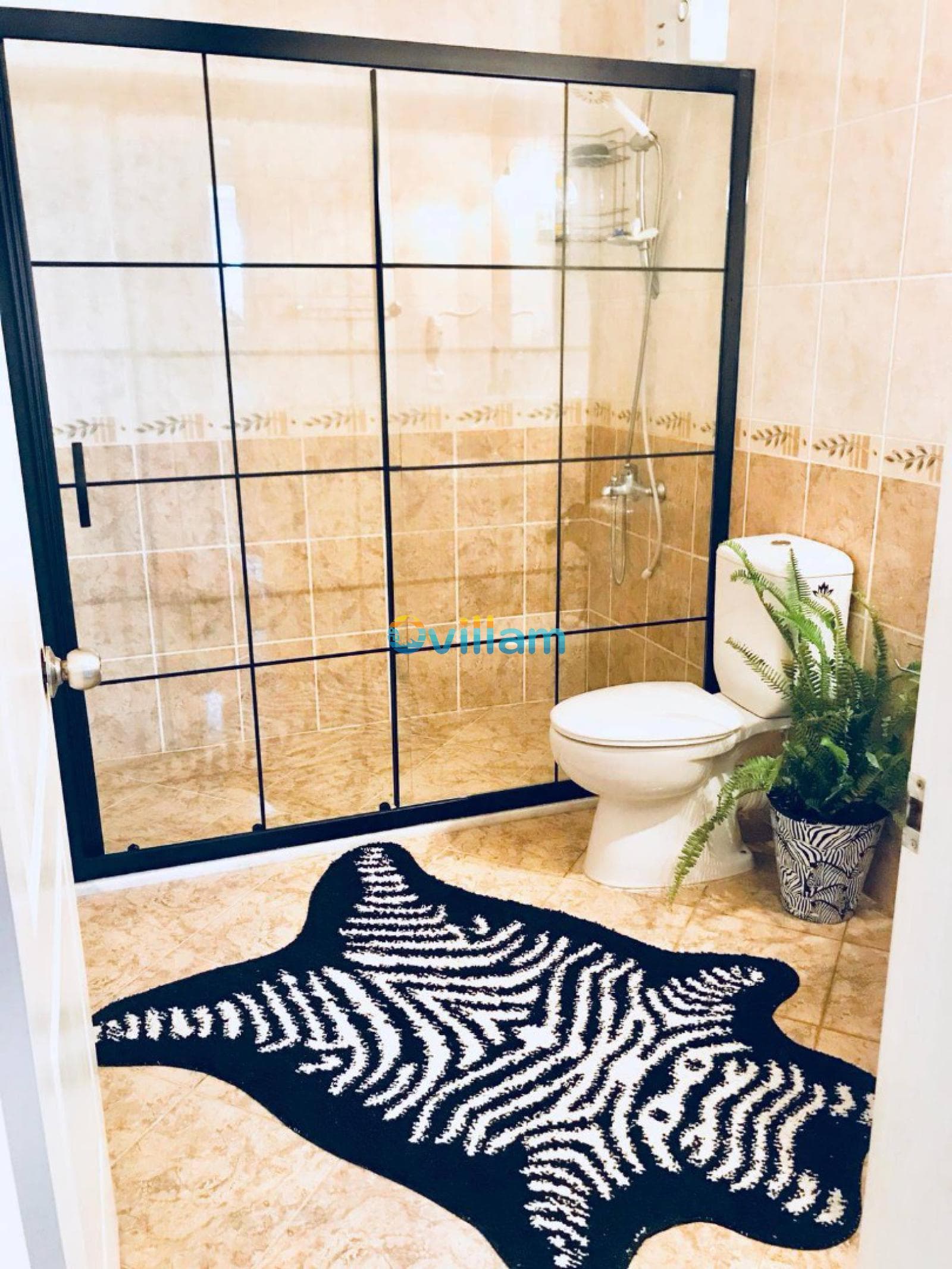 Siyah çerçeveli cam duşakabin ve klozetin yer aldığı banyo.