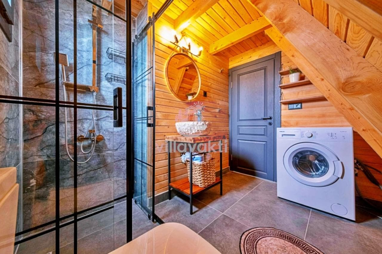 Ahşap duvarlı, duşakabinli ve çamaşır makineli banyo.
