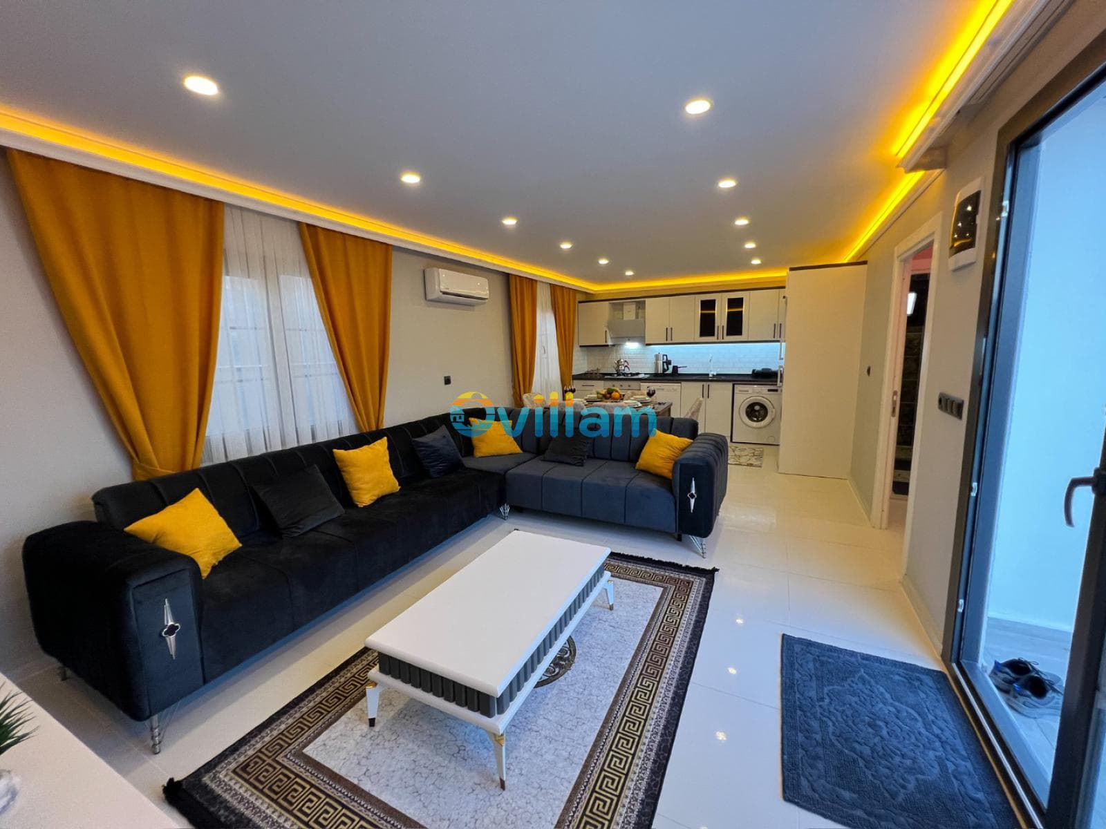 Sarı aksesuarlı siyah köşe koltuk ve beyaz sehpanın yer aldığı modern iç mekan.