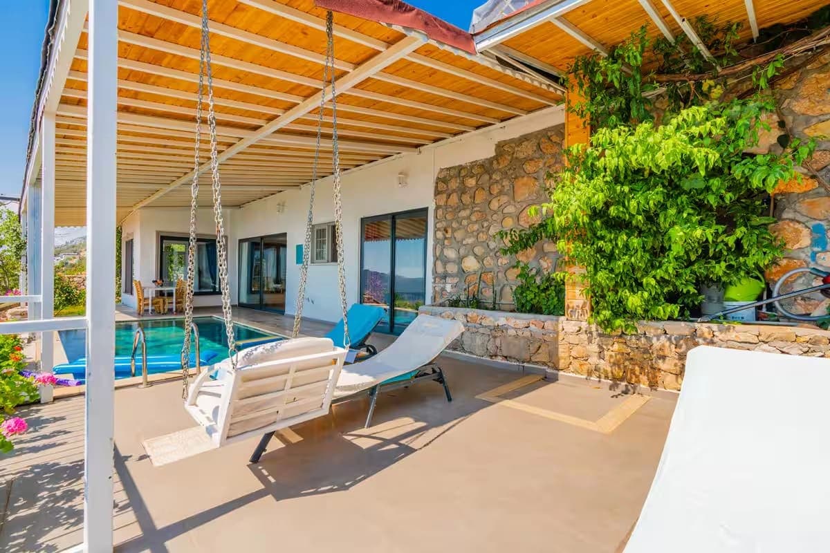 Verandada asılı salıncak ve şezlongların bulunduğu havuz kenarı