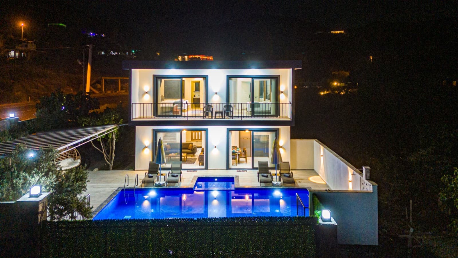 Işıklandırılmış havuzu ve iki katlı cephesiyle akşam vakti villa