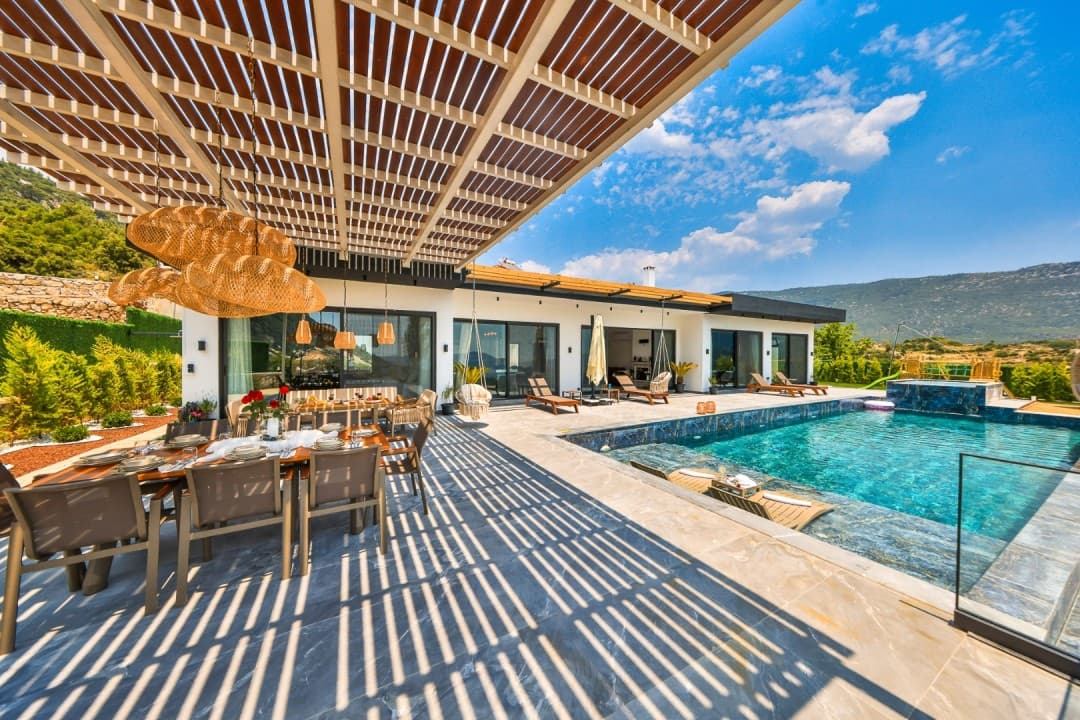 Havuz kenarında ahşap pergola altında yemek masası ve şezlonglar.