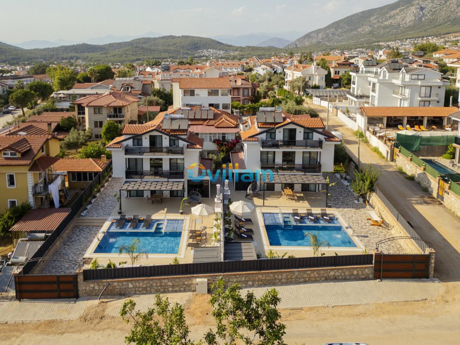 Havuzlu ikiz villalar ve dağ manzaralı yerleşim alanı.