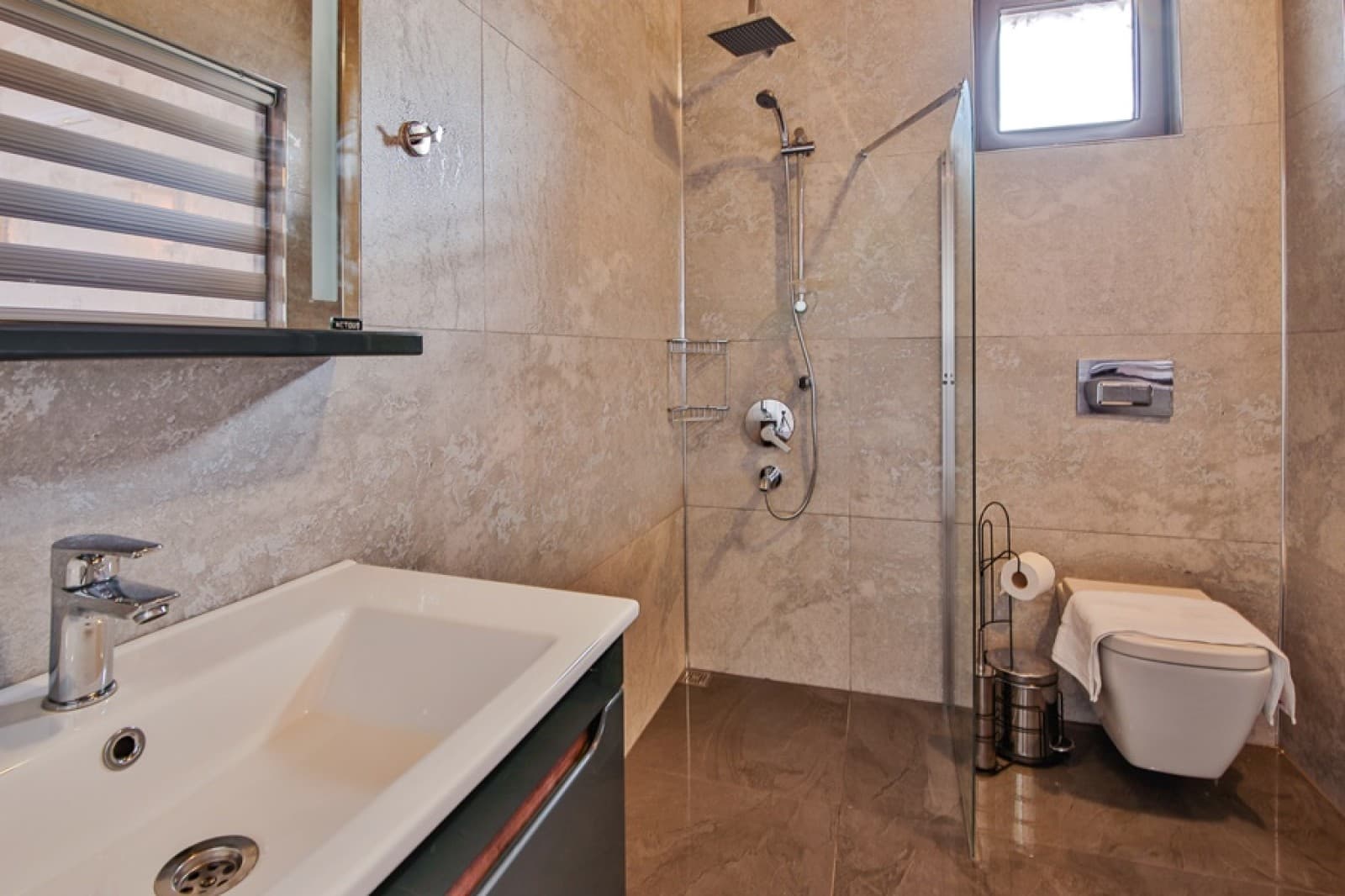 Bej seramik kaplı modern banyoda duşakabin ve lavabo.