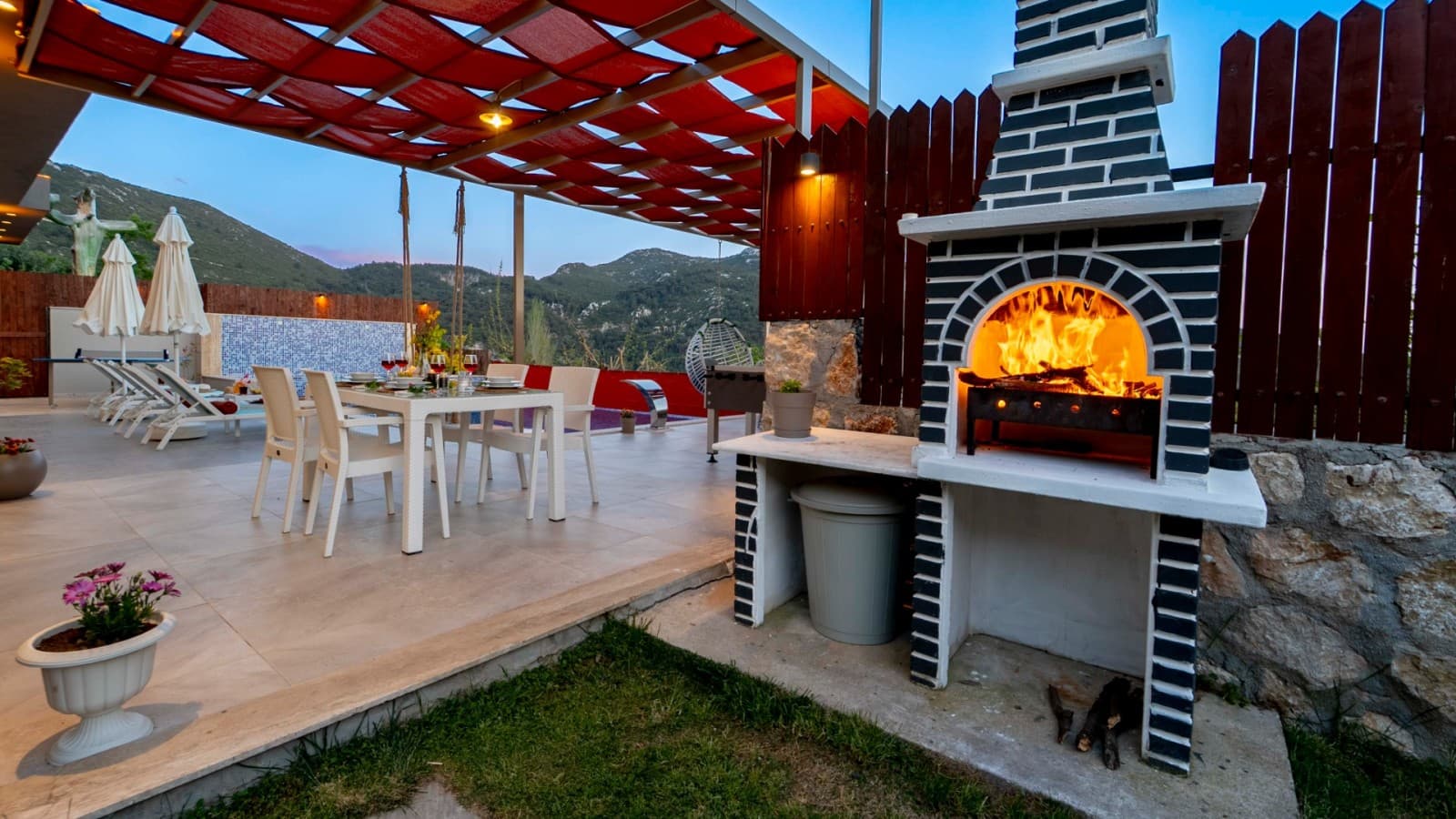 Teras alanında taş barbekü ve yemek masası.
