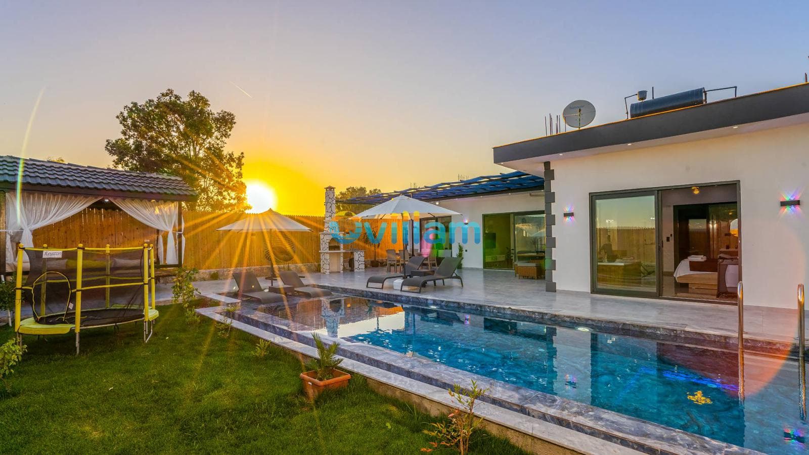 Gün batımında havuzlu villa bahçesi, şezlonglar ve kamelya.