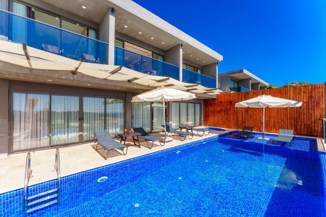 Büyük mavi havuzlu iki katlı modern villanın dış cephesi.