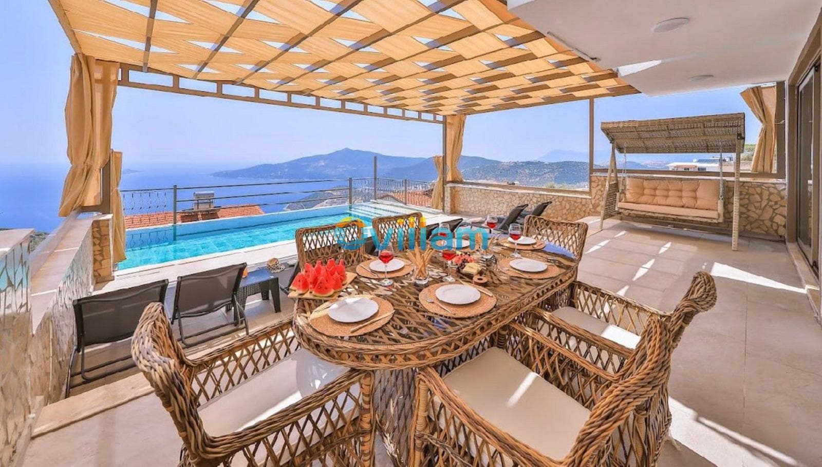 Güneşlikli terasta havuz, yemek masası ve deniz manzarası bulunuyor.