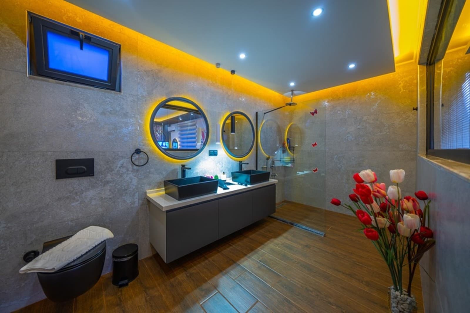 Sarı led ışıklandırmalı, iki aynalı ve siyah lavabolu modern banyo.