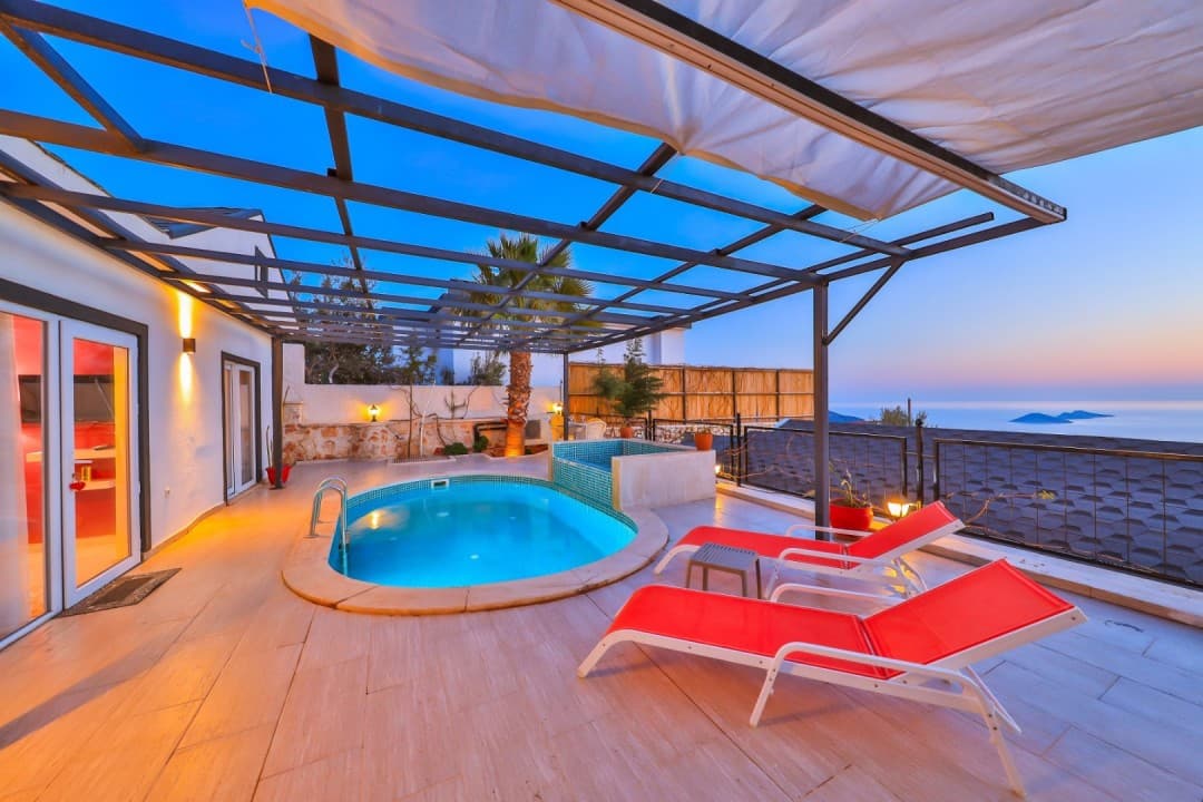 Akşam vakti havuz ve şezlongların bulunduğu, ferforje tavanlı villa terası.