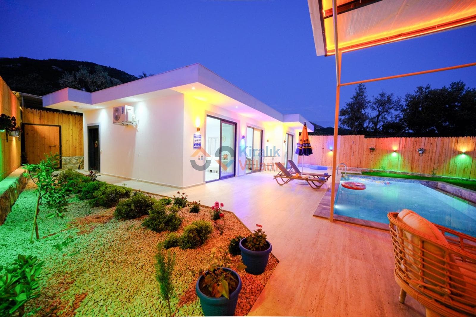 Bahçesinde havuz ve şezlonglar bulunan beyaz villa