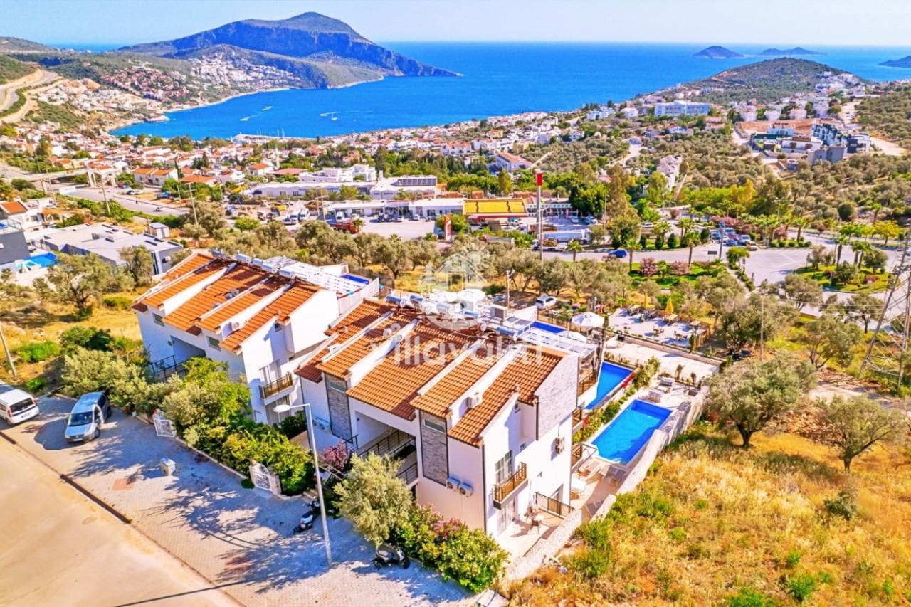 Deniz manzaralı yamaca kurulmuş villalar ve havuzları, kuşbakışı dış cephe görünümü.