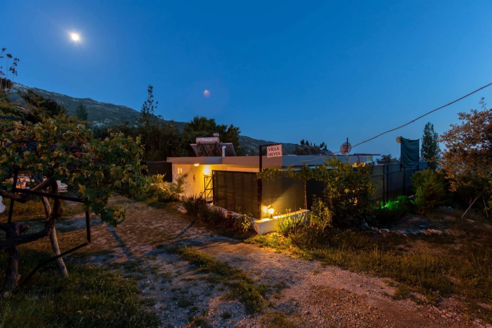 Gece vakti aydınlatmalı dış cephesi ve tabelası görünen tek katlı villa.