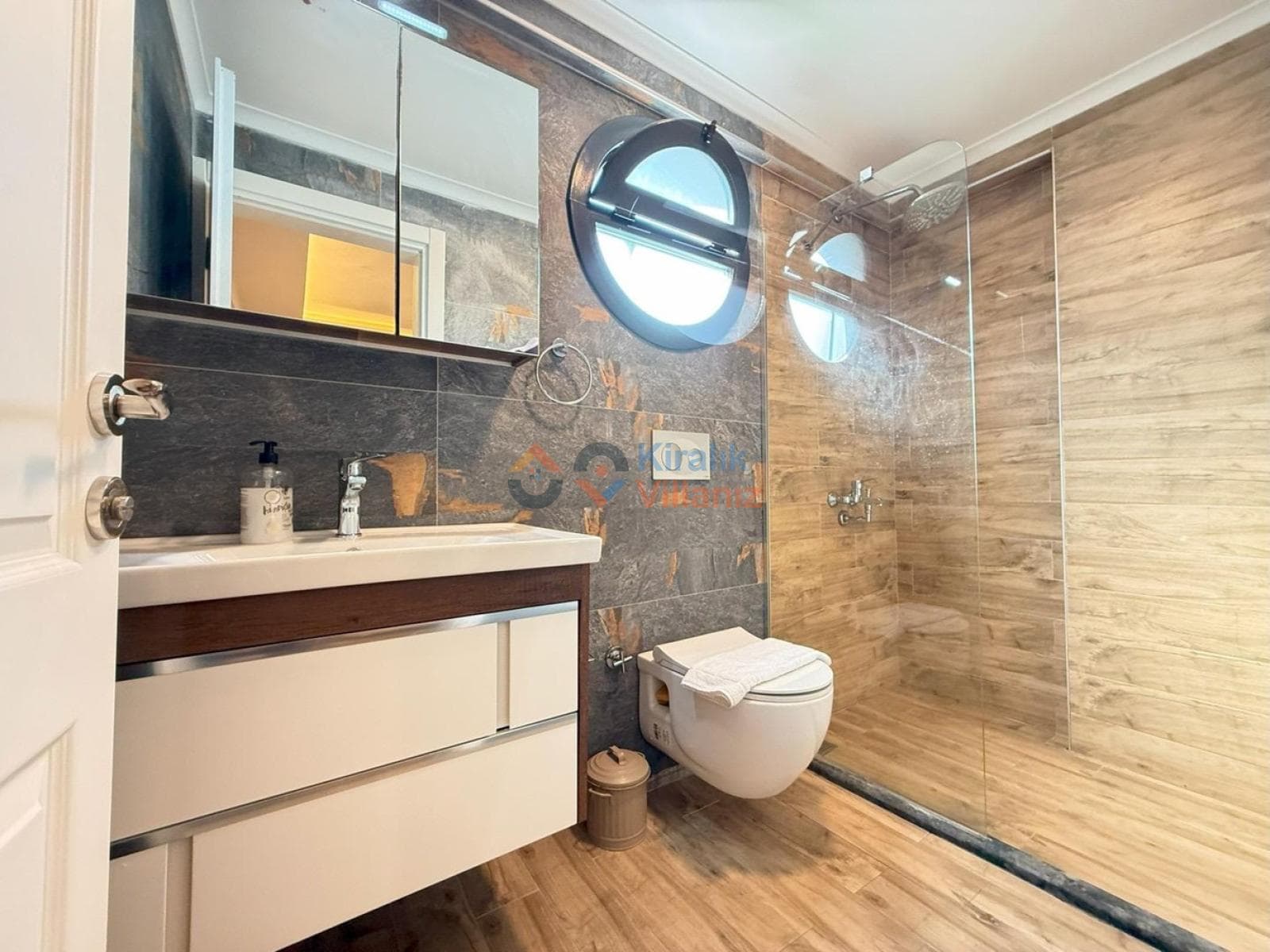 Ahşap ve taş detaylı duş alanı olan, modern lavabolu banyo.