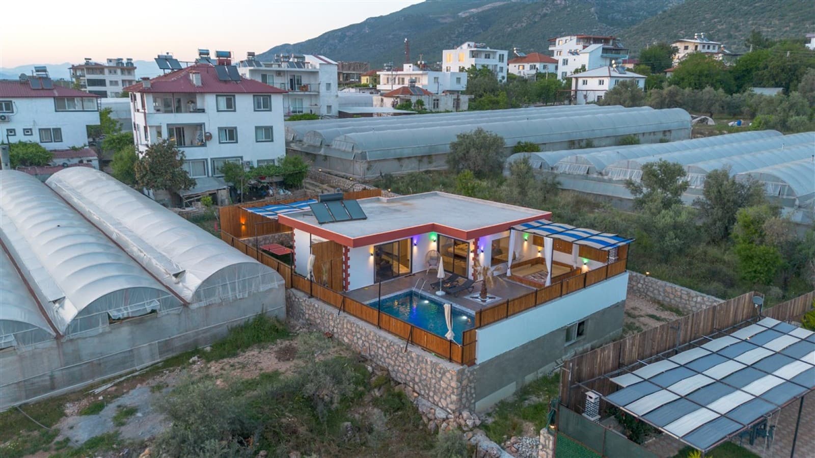 Seralarla çevrili bölgede tek katlı havuzlu villa.