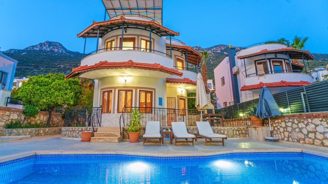 Çok katlı villanın ön cephesinde şezlongların yer aldığı havuz alanı.