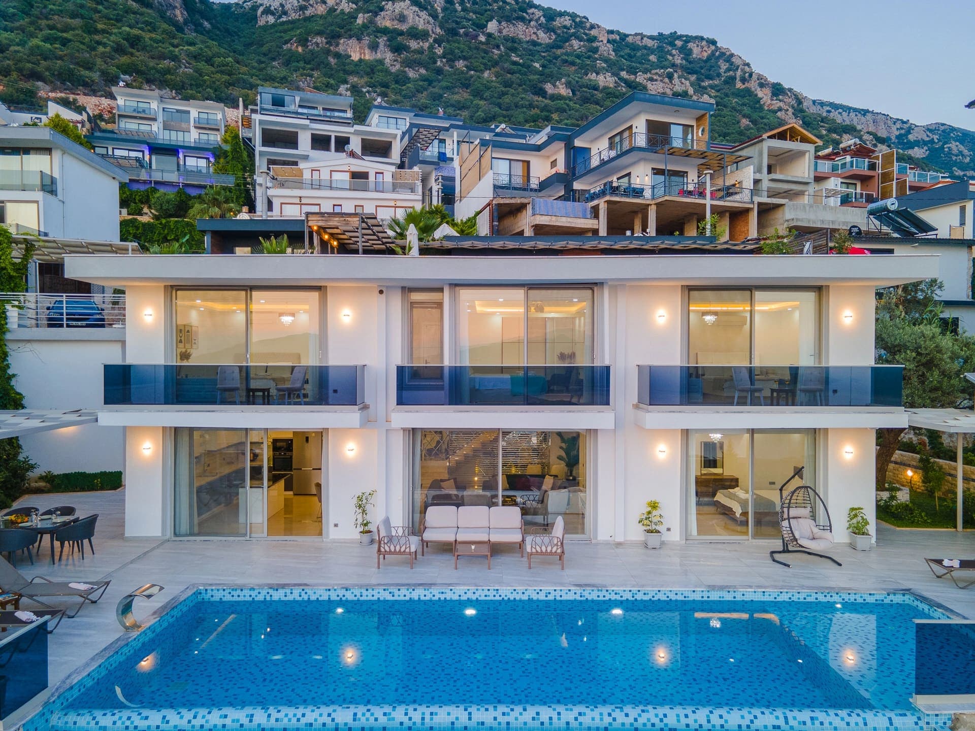 Önünde havuz bulunan, dağ yamacındaki iki katlı modern villanın dış cephesi.