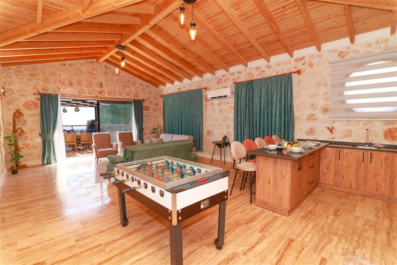 Ahşap tavanlı geniş salonda langırt masası ve ada mutfak.