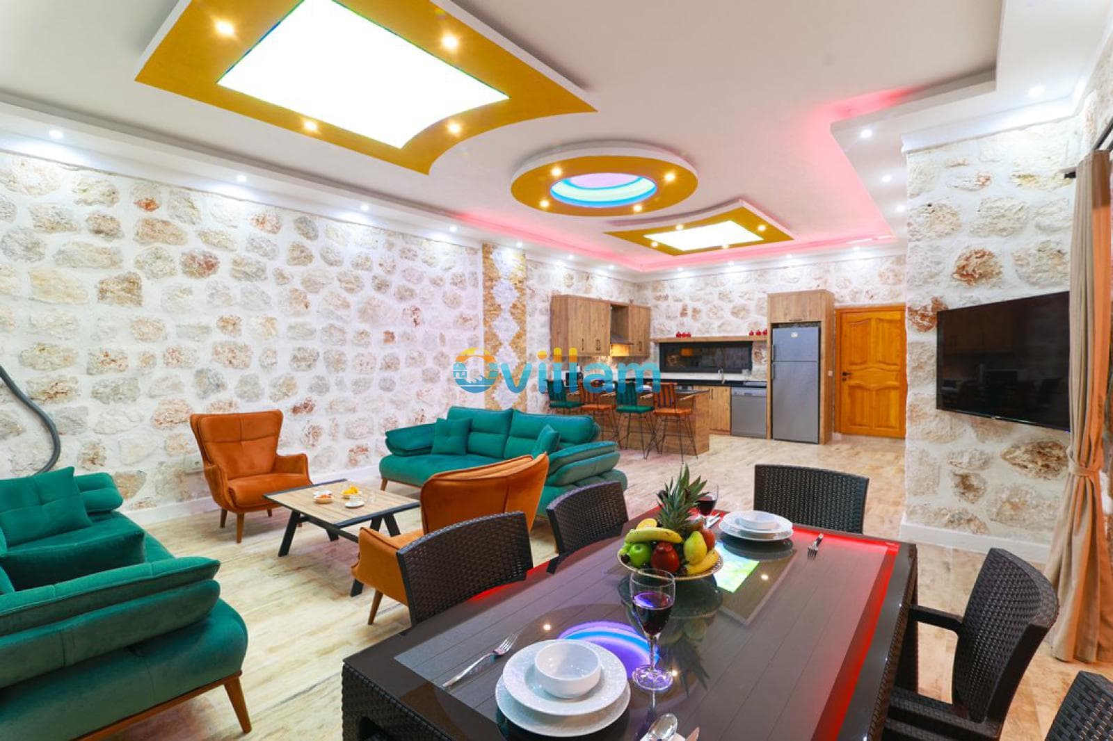 Taş duvarlı, oturma grubu ve yemek masası bulunan geniş iç mekan.
