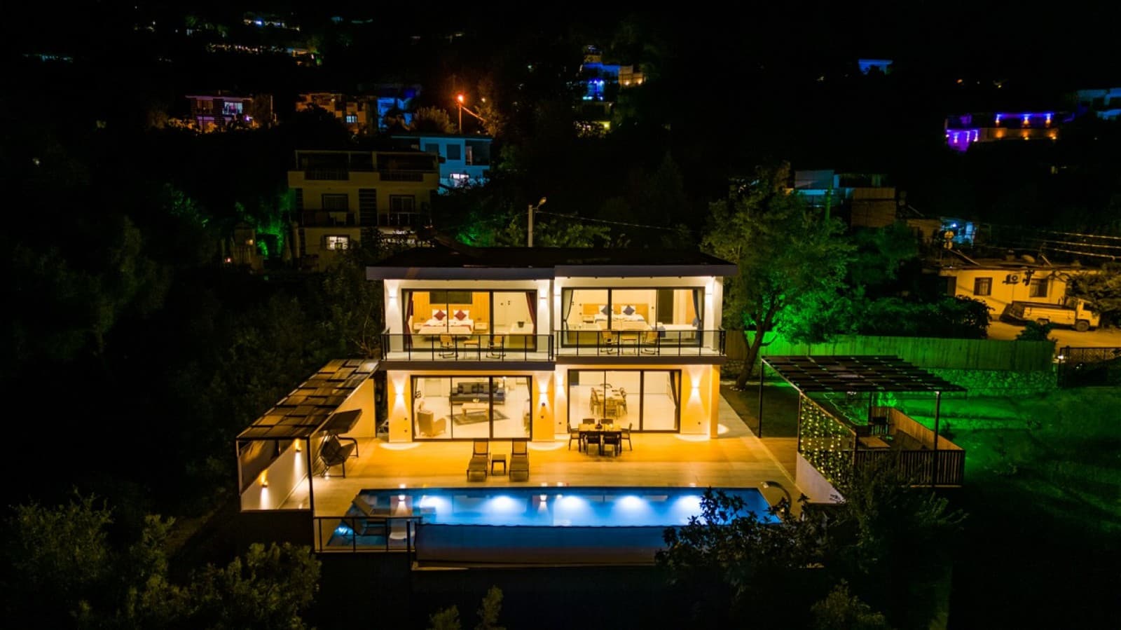 Geceden çekilen havuzlu ve aydınlatmalı villanın dış cephe görünümü.