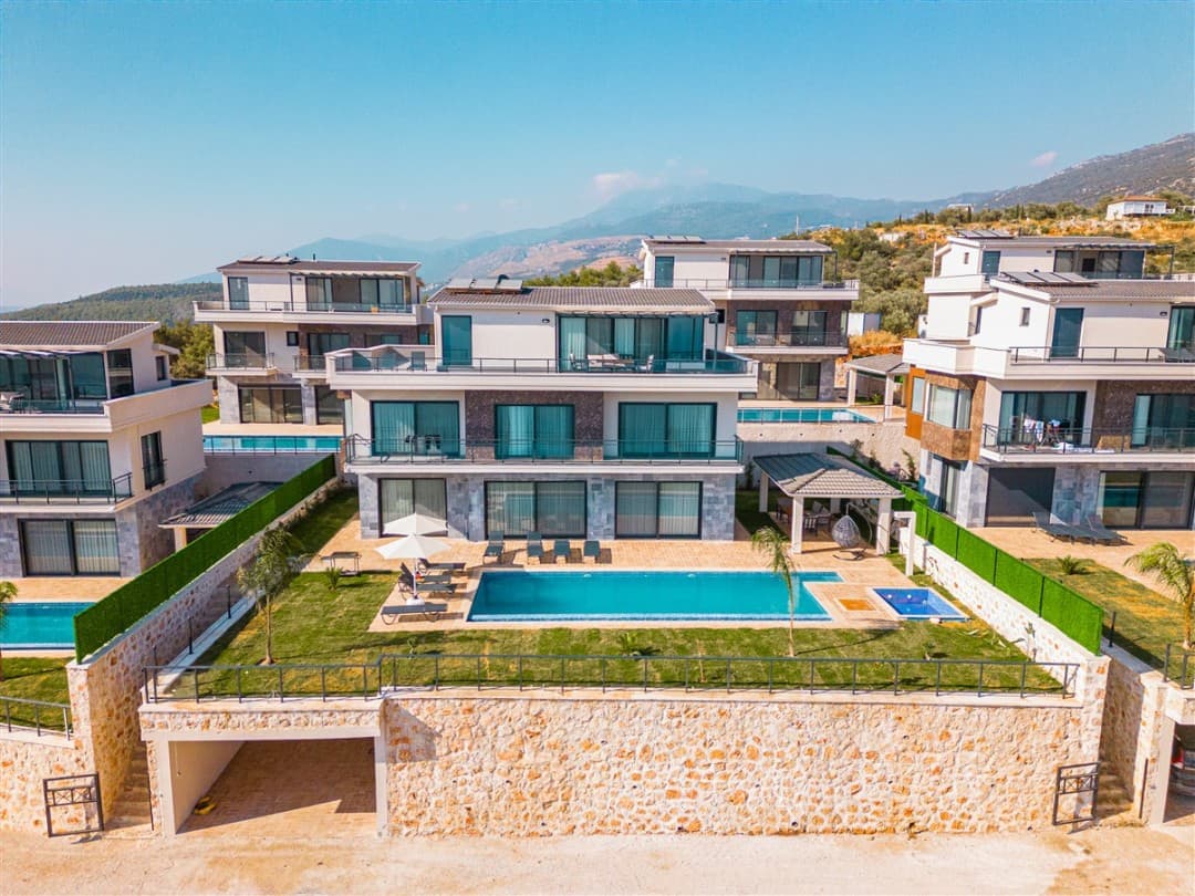 Yüksekten çekilmiş, havuzlu ve bahçeli modern villaların genel yerleşim görünümü.
