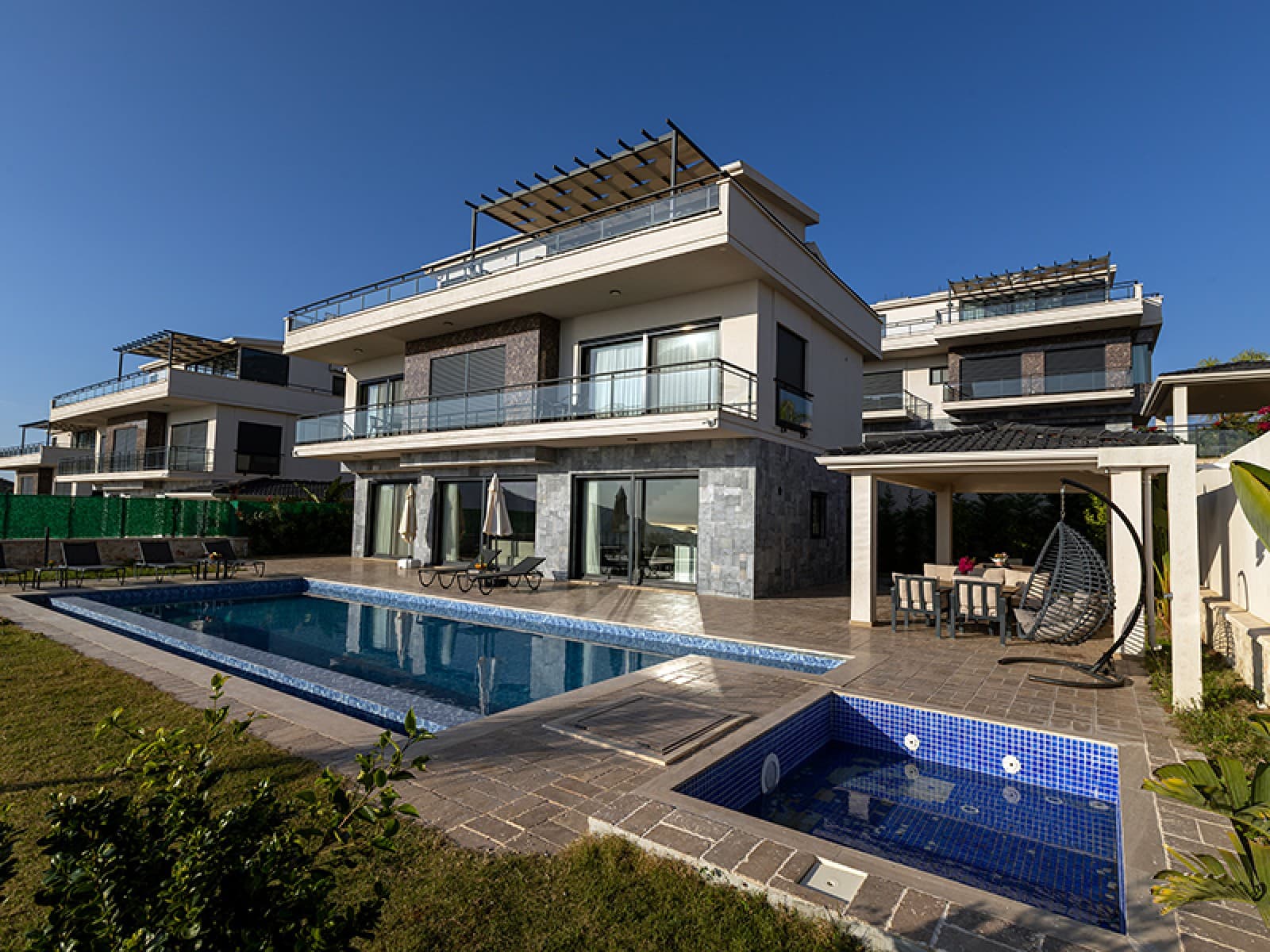 Önünde havuz ve kamelya alanı olan lüks villa dış görünümü.