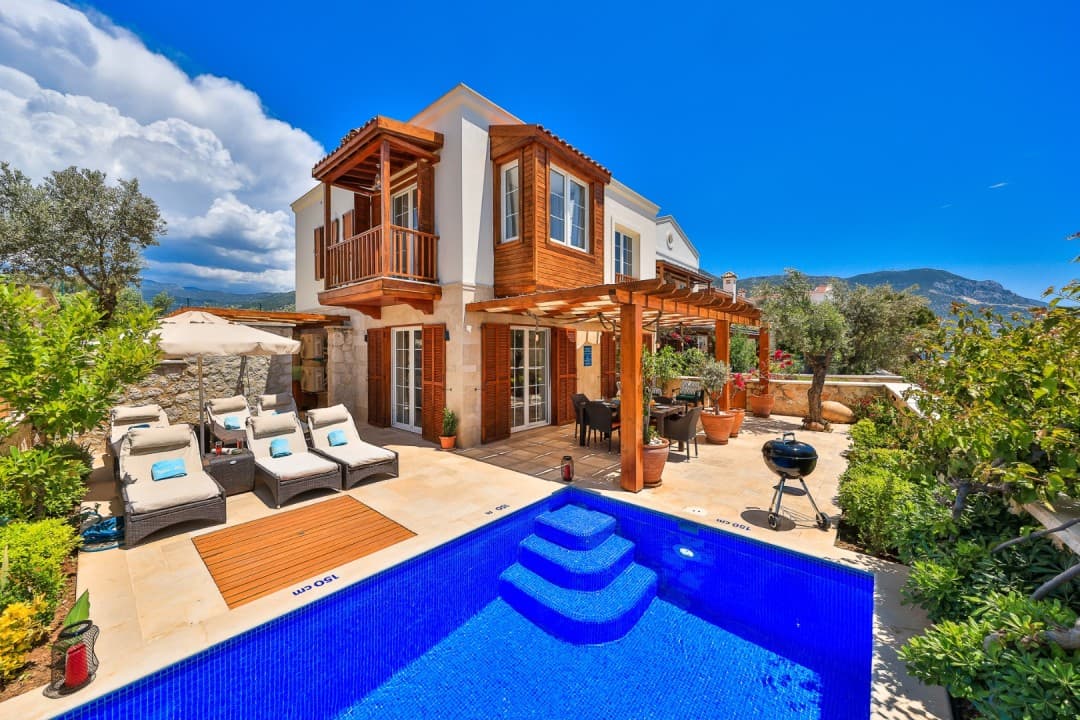 Ahşap detaylı iki katlı villa ve mavi havuzlu bahçesi.