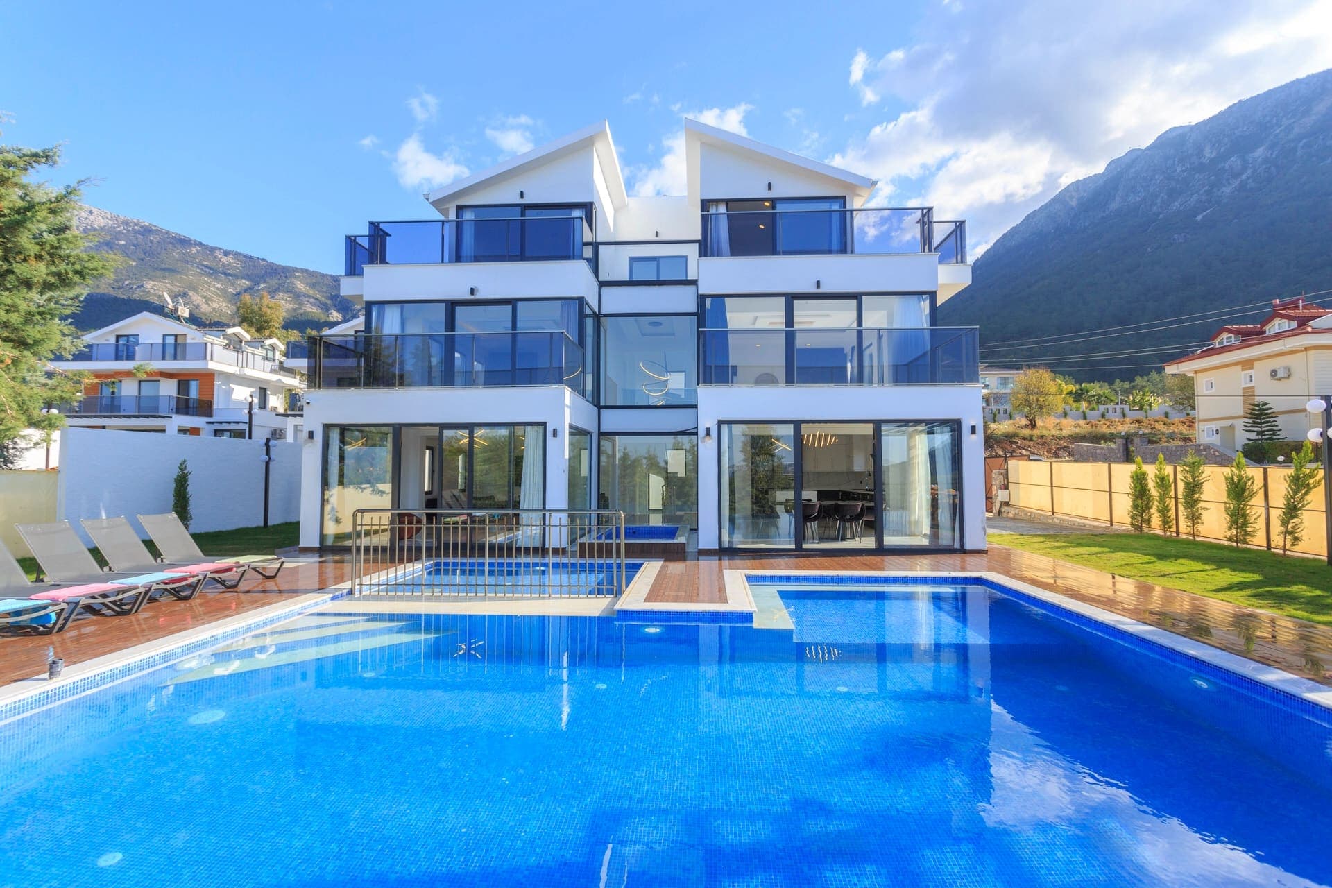 Dağ manzaralı havuz başında şezlongları bulunan modern villa.
