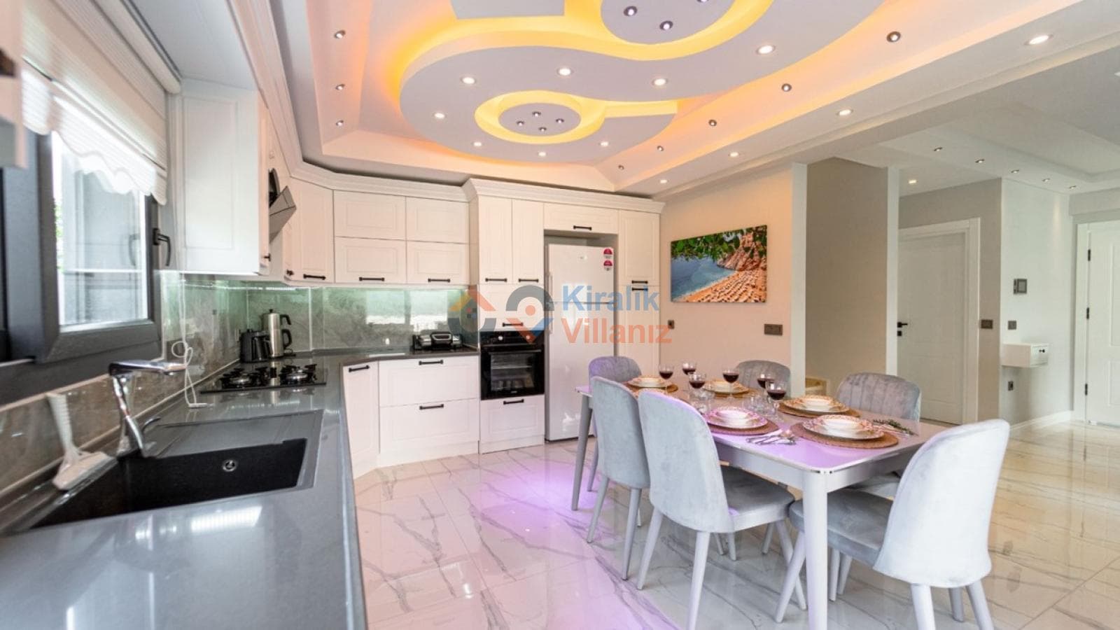 Işıklı modern tavanı olan beyaz mutfak ve yemek masası.