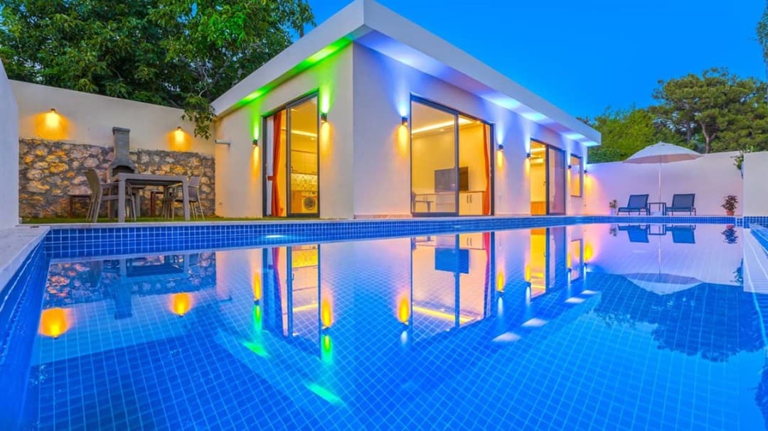 Renkli dış aydınlatmalı modern villanın havuzlu bahçesi.
