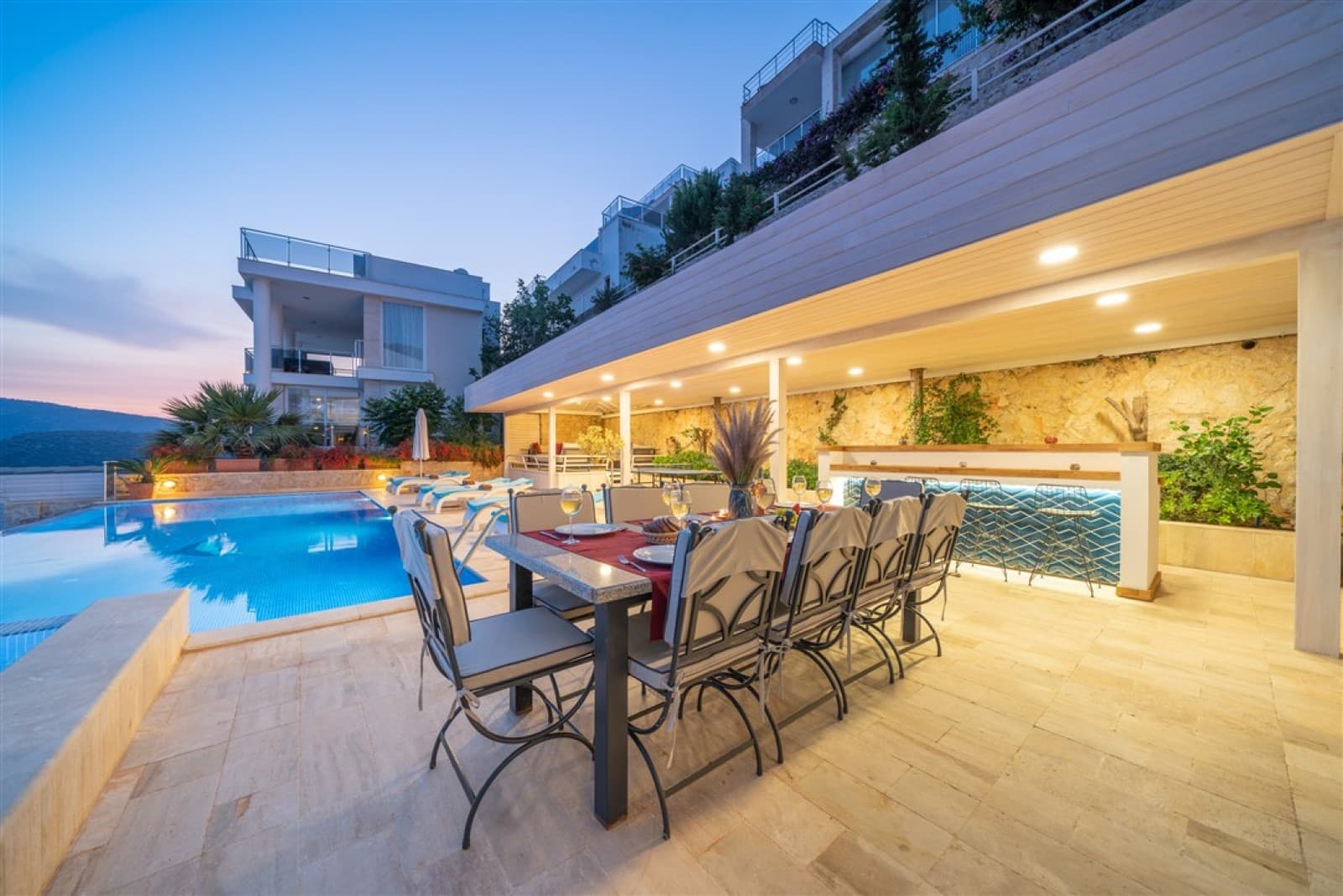 Havuz başındaki kapalı terasta yemek masası ve sandalyeler.