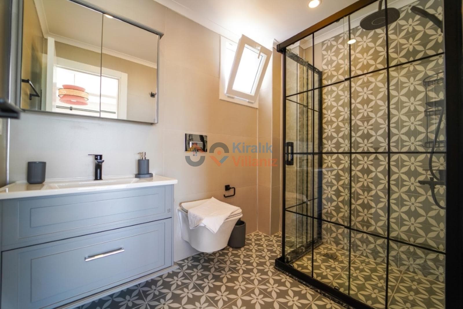 Gri dolaplı lavabo ve siyah çerçeveli duşakabinin olduğu banyo