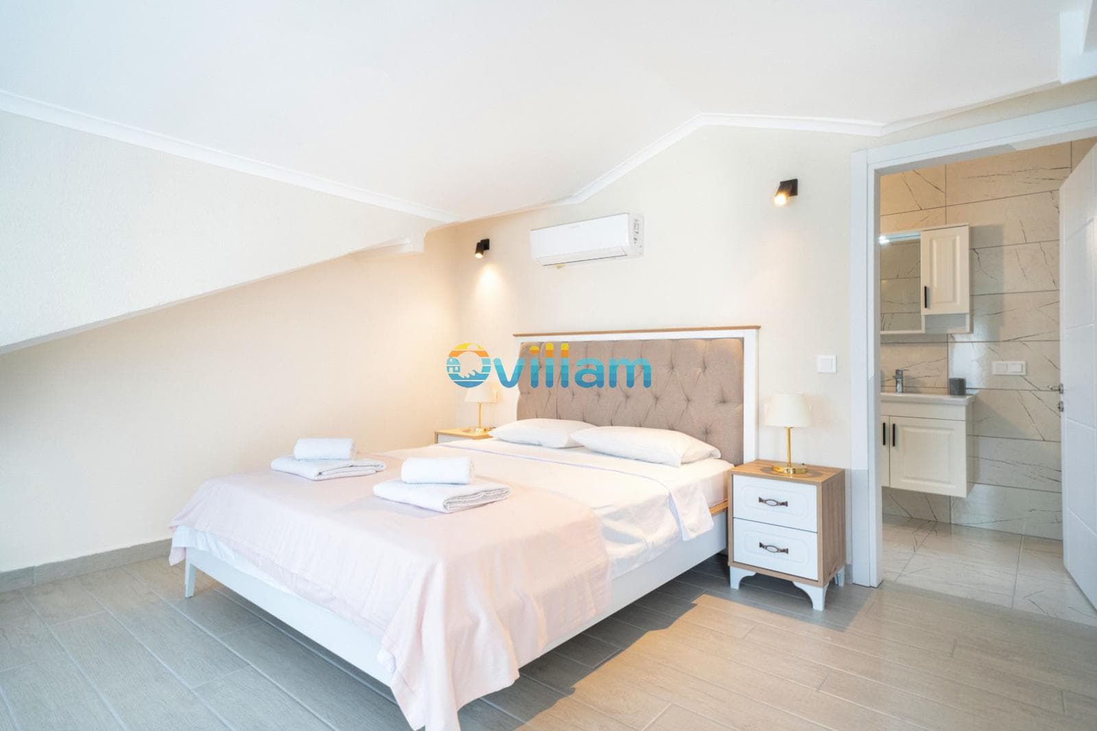 Çift kişilik yatak, komodinler ve açık renkli banyo kapısı olan yatak odası