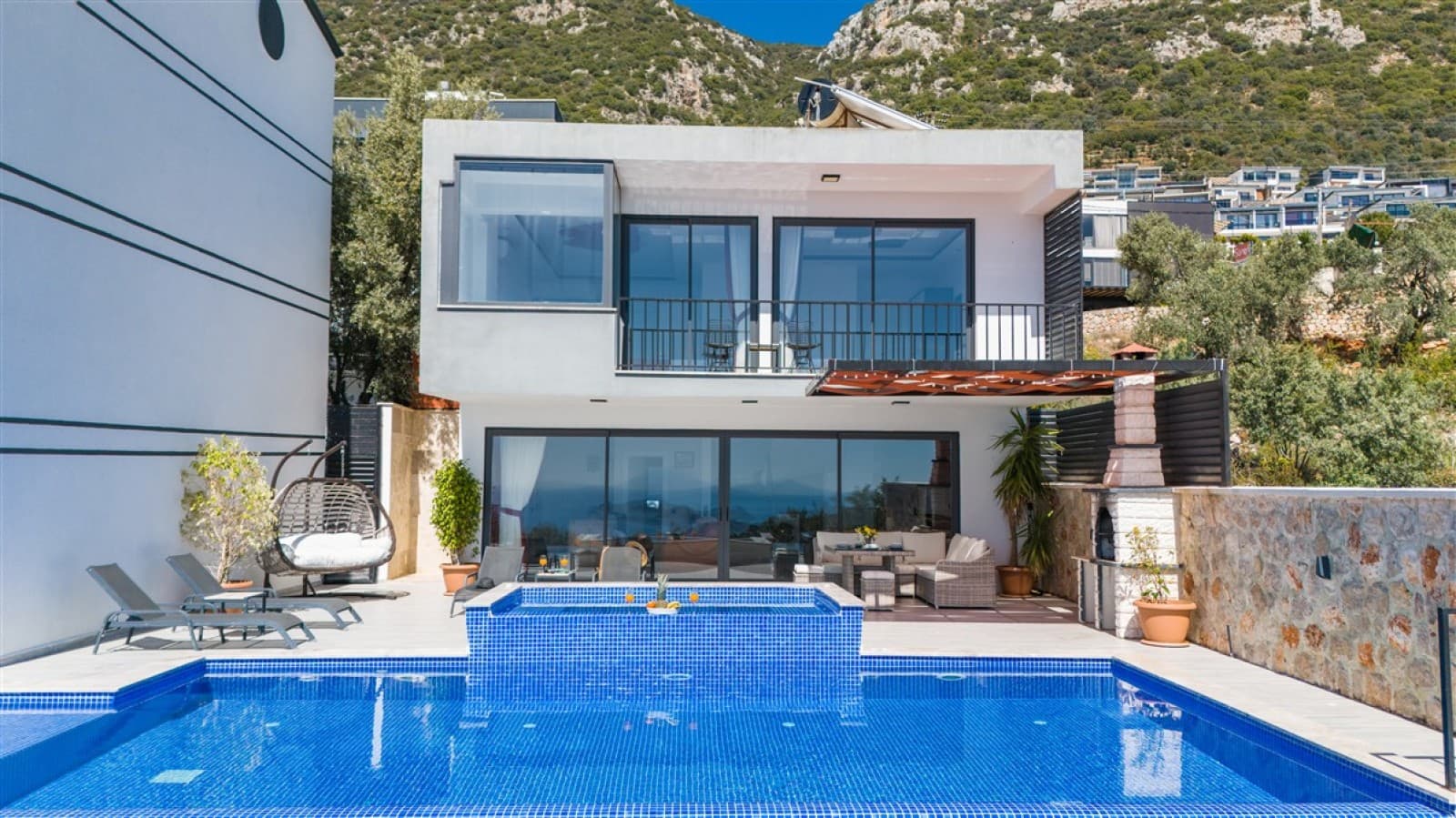 Bahçesinde havuz ve şezlonglar bulunan modern beyaz villa.