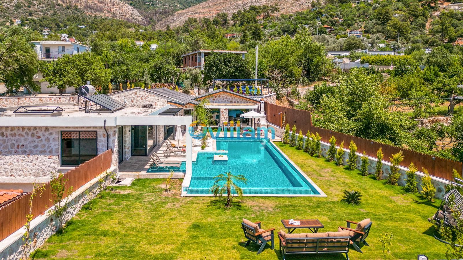 Doğa manzaralı, havuzlu ve geniş bahçeli villanın yüksekten görünümü.