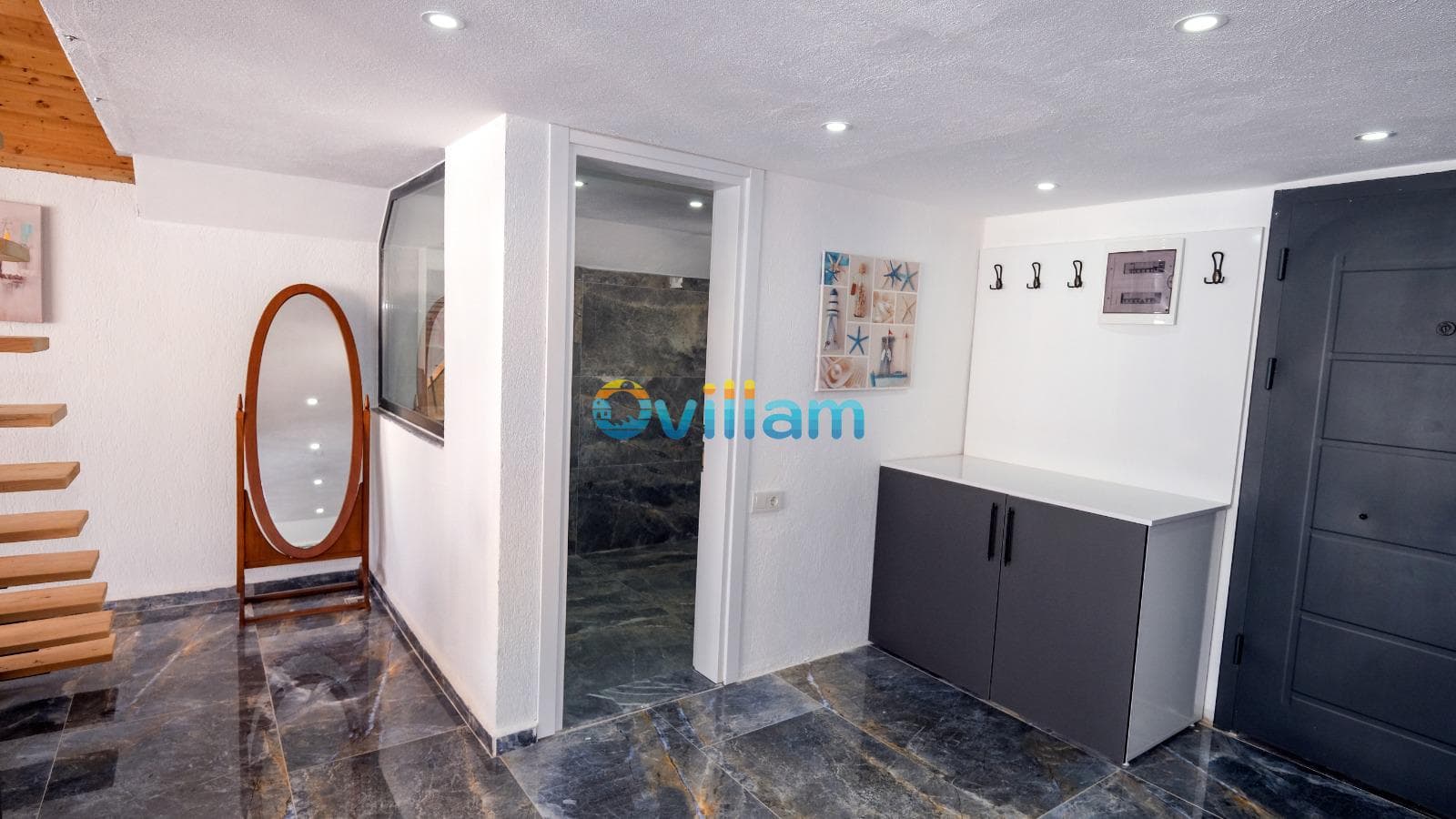 Ahşap merdivenli, mermer zeminli antrede boy aynası, vestiyer ve banyo kapısı bulunuyor.