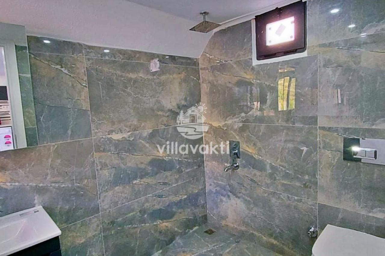 Gri mermer kaplı duvarları olan duş alanı ve lavabo.