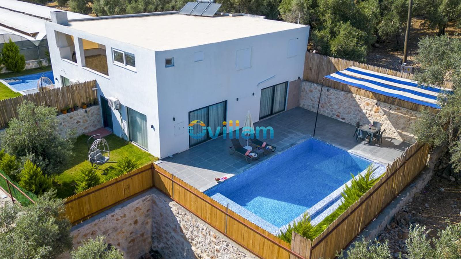 Zeytin ağaçlarıyla çevrili havuzlu ve oturma alanlı iki katlı beyaz villa