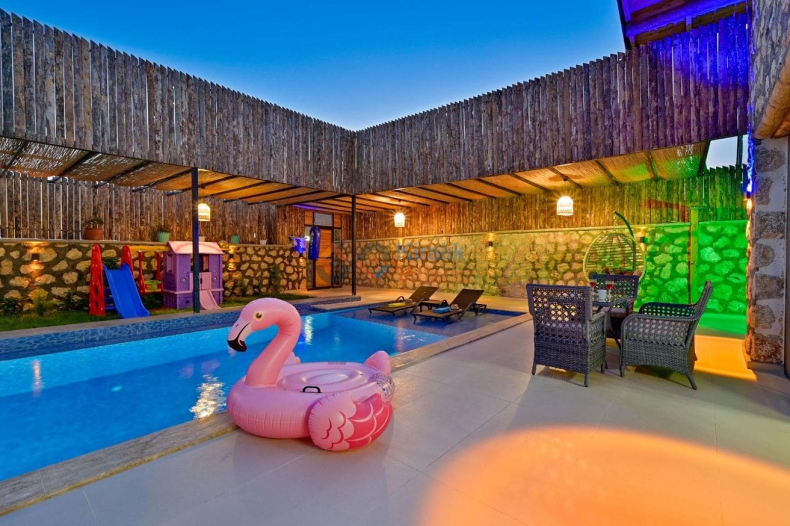 Akşam aydınlatmalı havuz kenarında flamingo simit ve çocuk oyun alanı