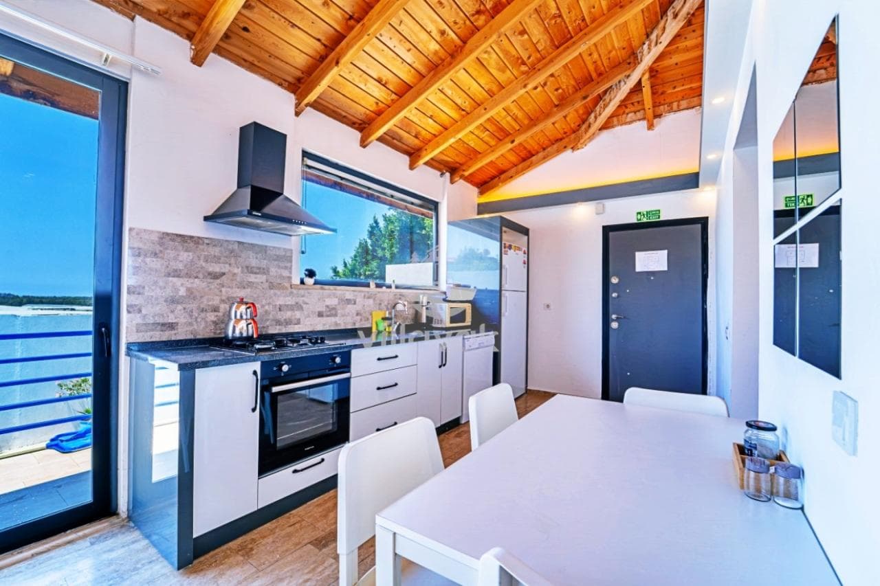 Ahşap tavanlı, gri dolaplı modern mutfak ve yemek masası.