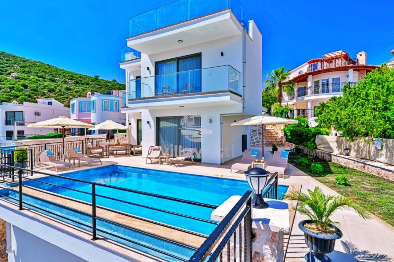 Önünde havuz ve şezlonglar bulunan iki katlı beyaz modern villa.