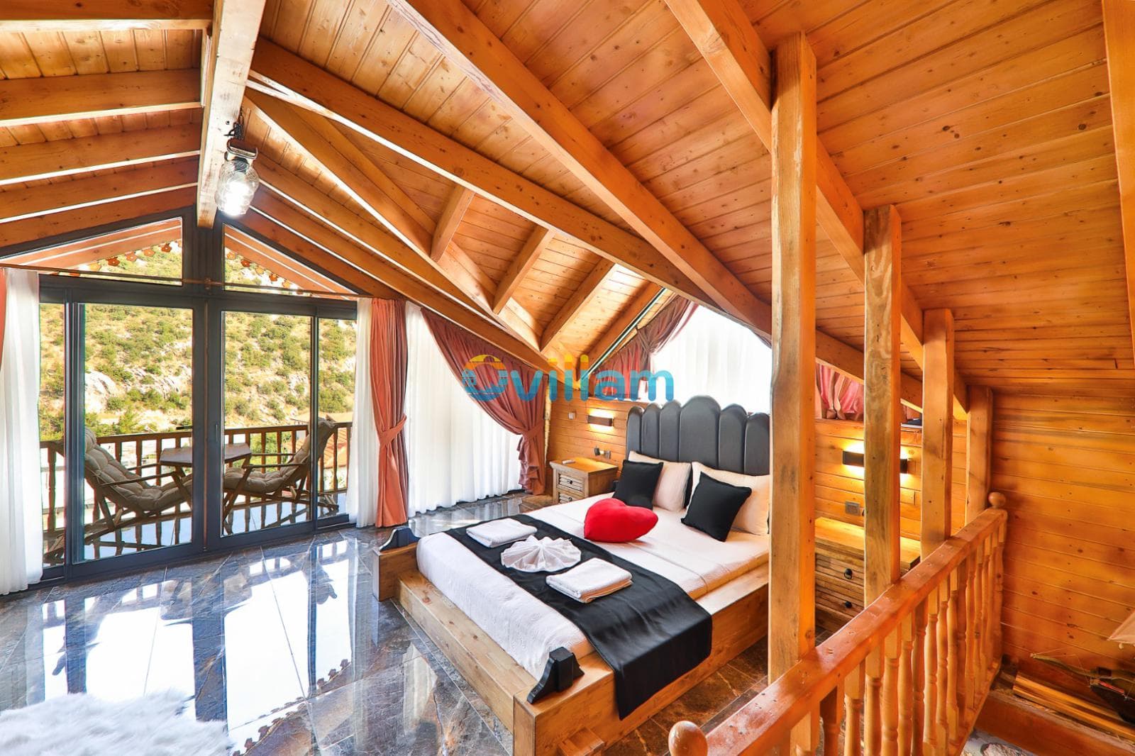 Ahşap tavanlı çatı katı yatak odasında çift kişilik yatak ve balkon kapısı.