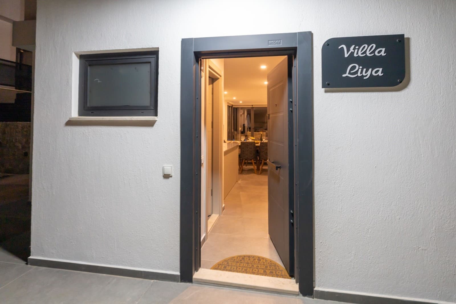 Duvarında Villa Liya tabelası asılı olan binanın açık gri giriş kapısı.