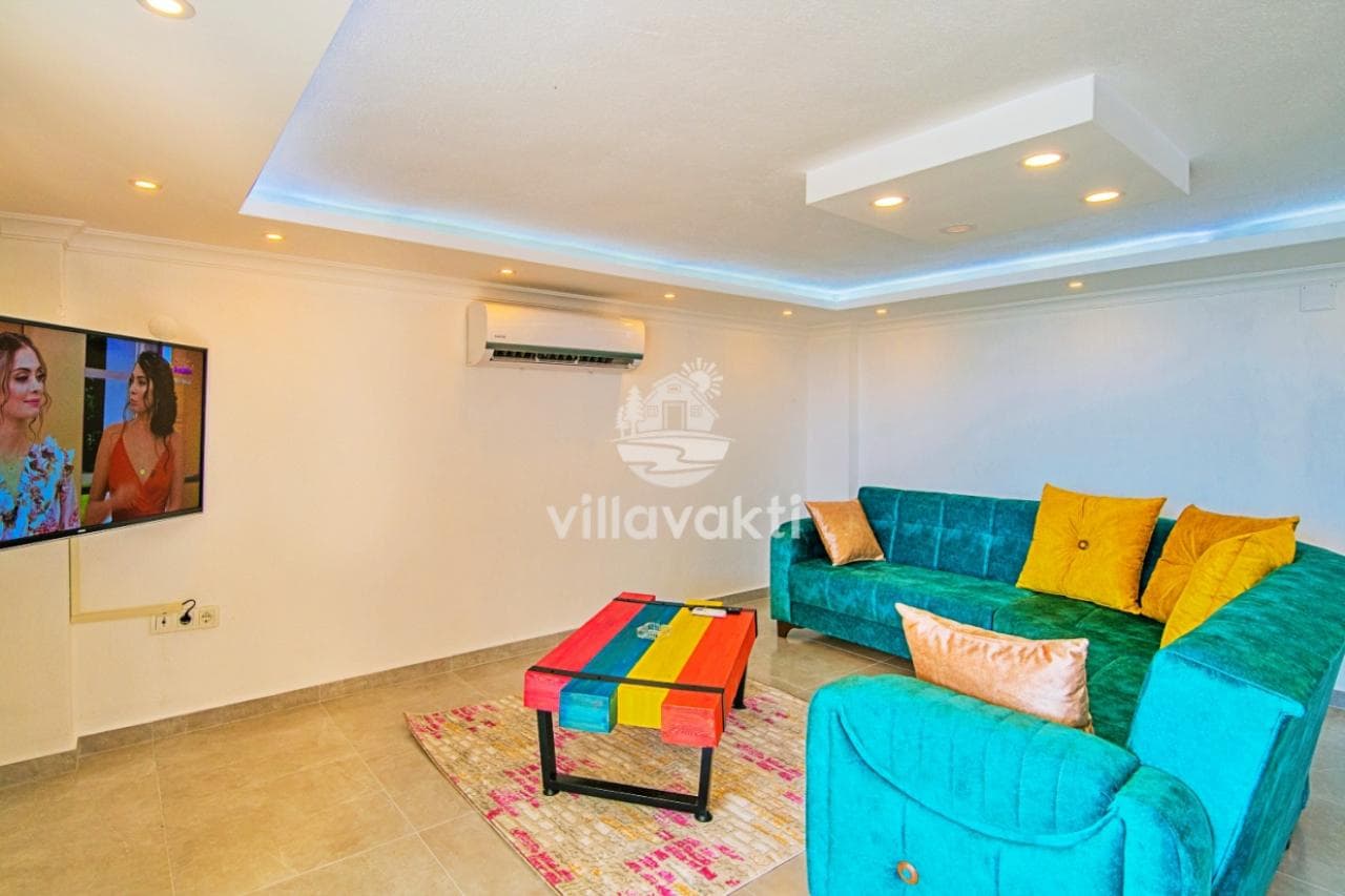 Yeşil koltuk takımı ve renkli orta sehpa bulunan aydınlık salon.