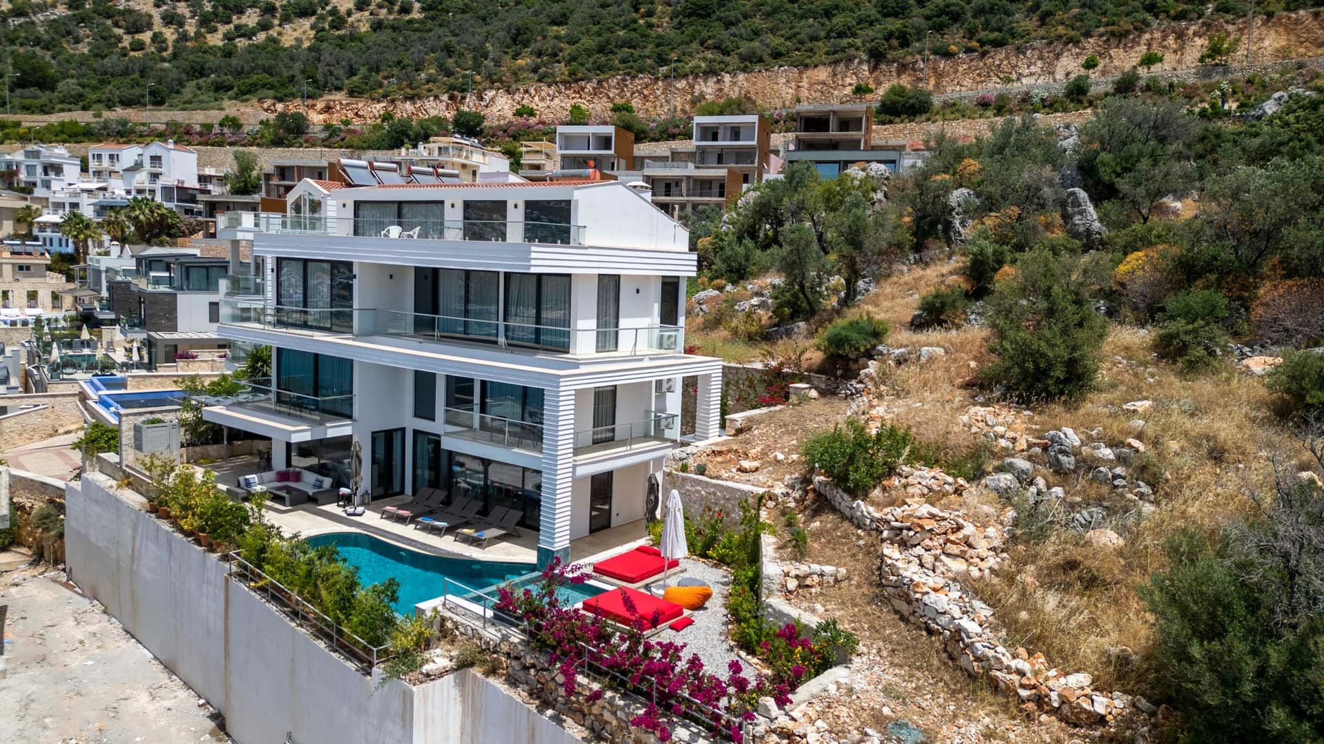 Doğa içinde konumlanan, teraslı ve havuzlu modern beyaz dış cephe.