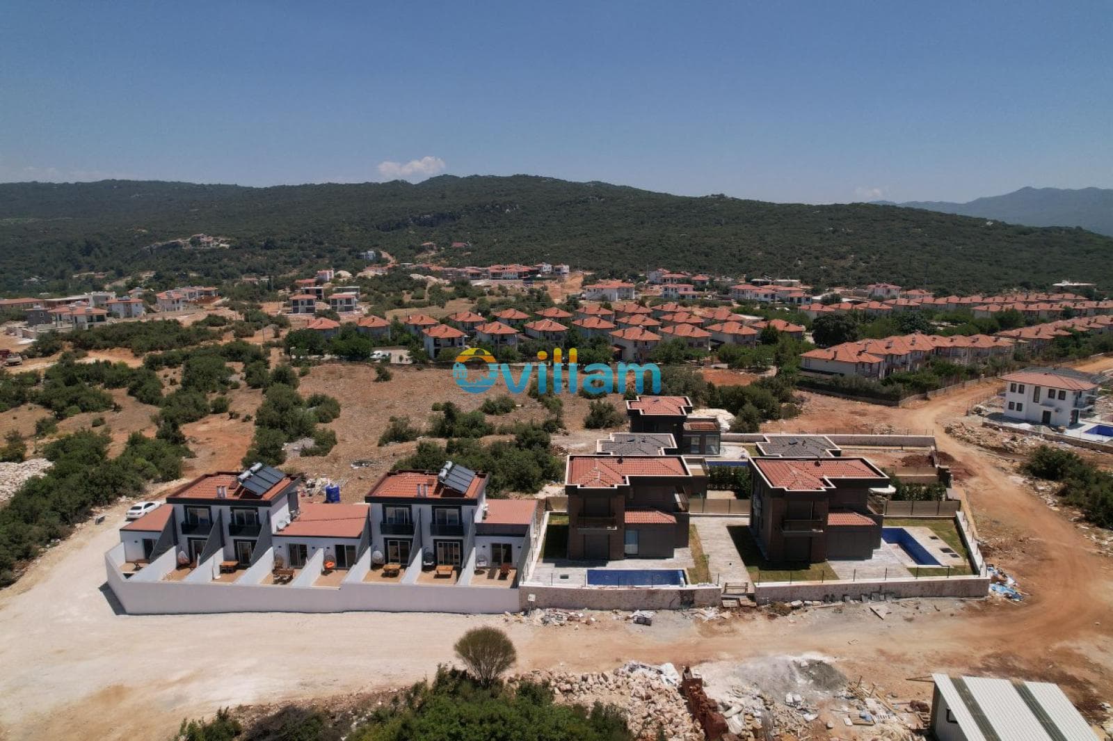 Kiremit çatılı villaların ve çevre yerleşimin kuş bakışı görünümü.
