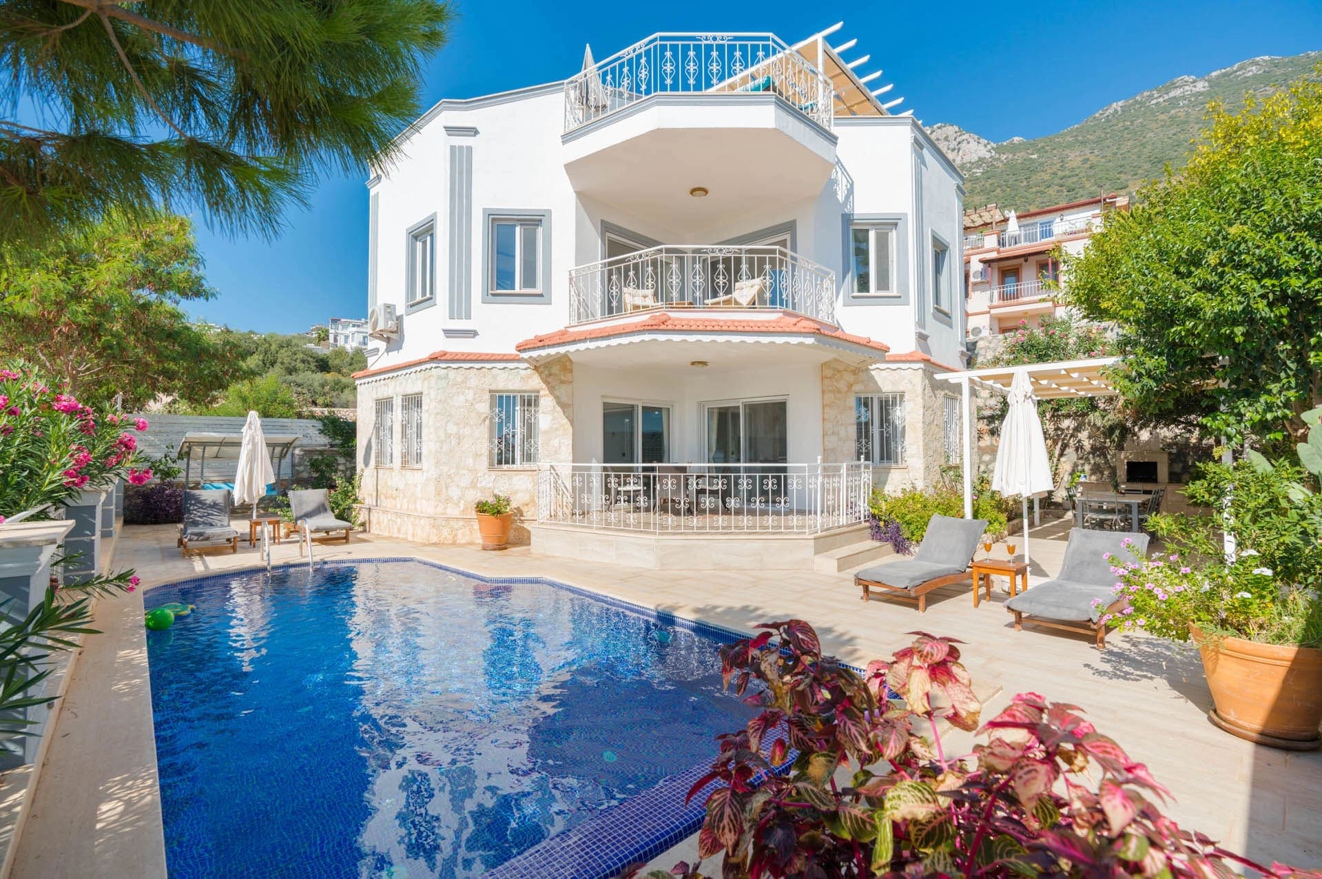 Bahçesinde havuz ve şezlonglar bulunan iki katlı villa.