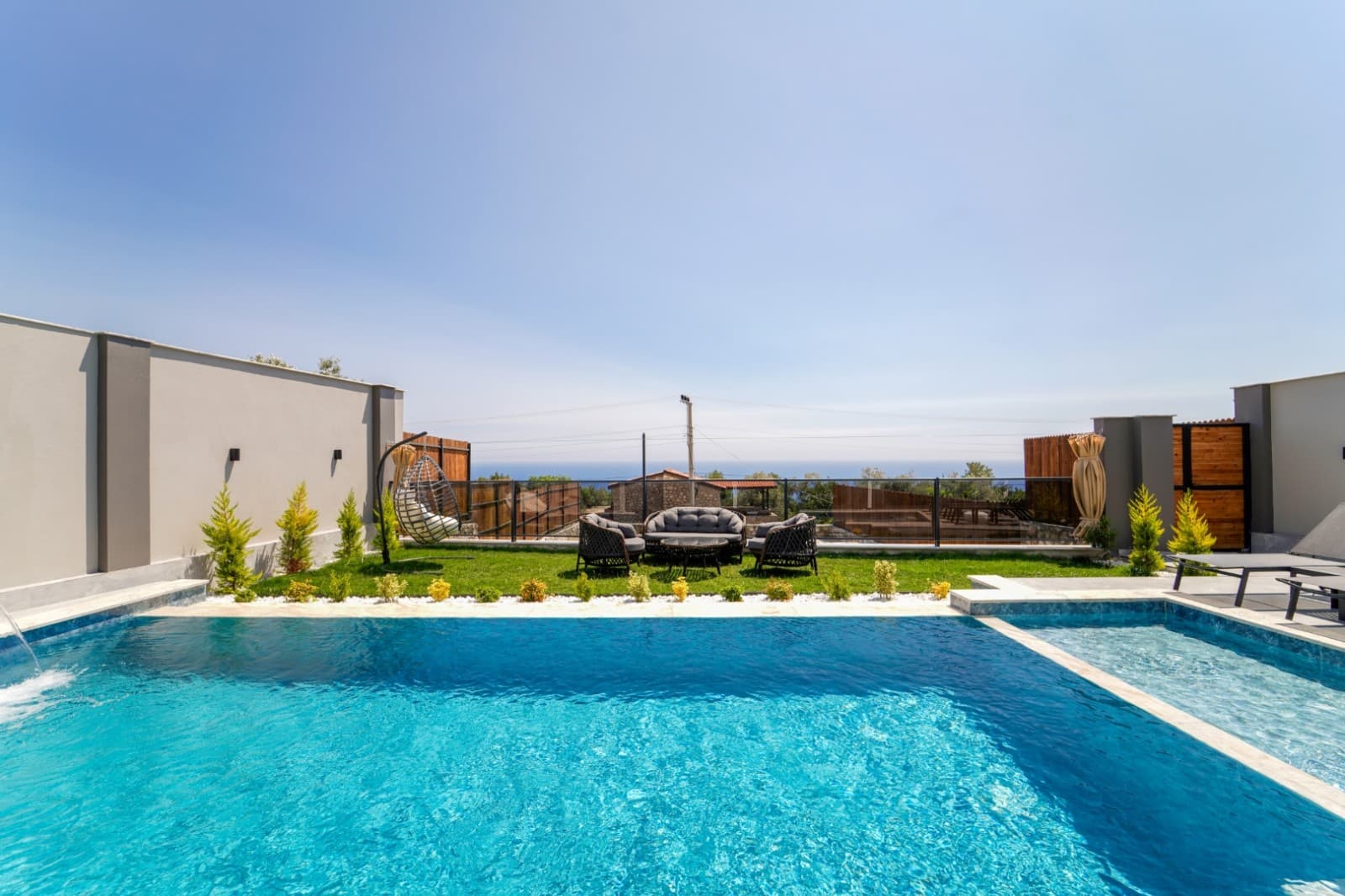 Bahçesinde oturma grubu bulunan, deniz manzaralı özel havuzlu villa.